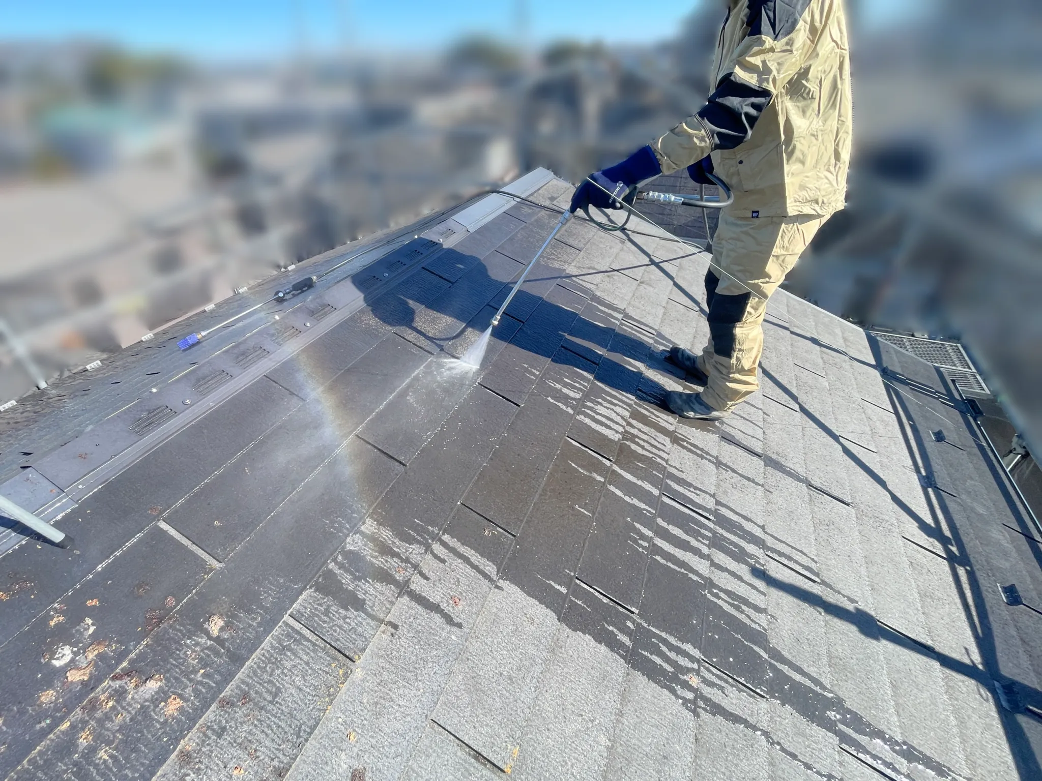 屋根の上を高圧洗浄機で洗浄中