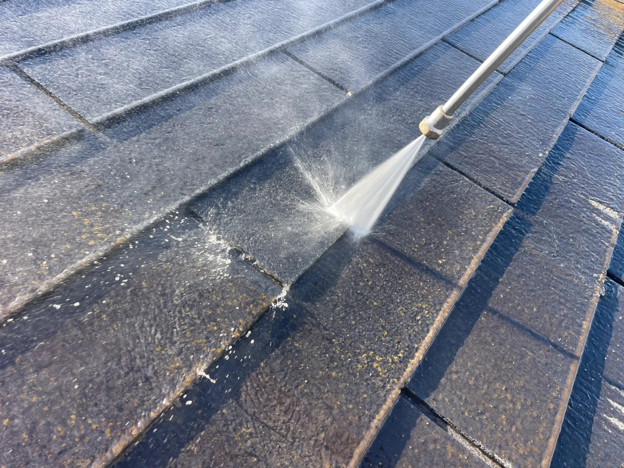 屋根の上を高圧洗浄機で洗浄中(アップ)